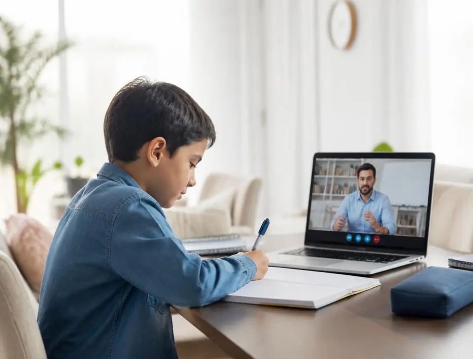A pupil writing notes while his teacher leads a live online lesson